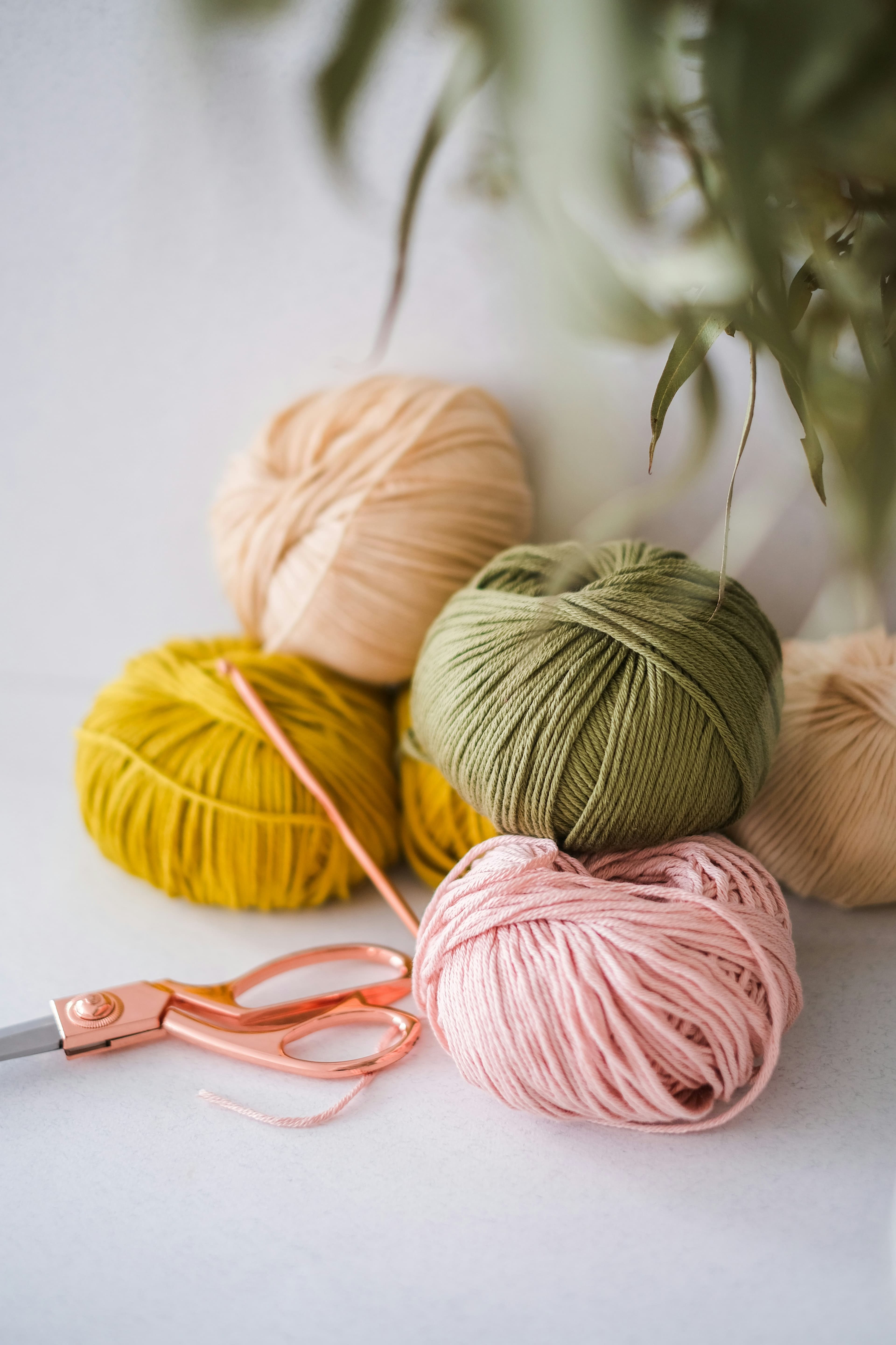 Artisan crochet colorful yarn balls and rose gold scissors background